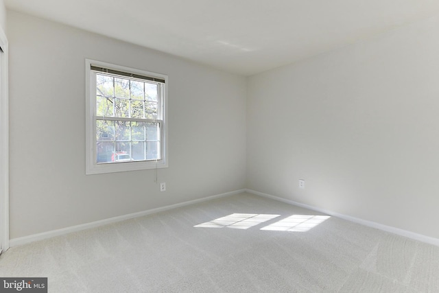 unfurnished room featuring baseboards and light colored carpet