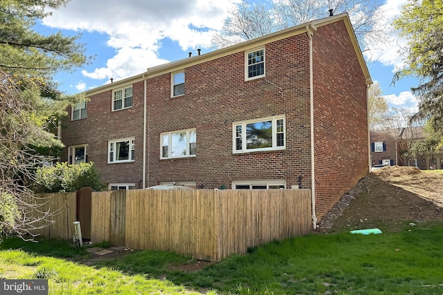 back of house with brick siding and fence