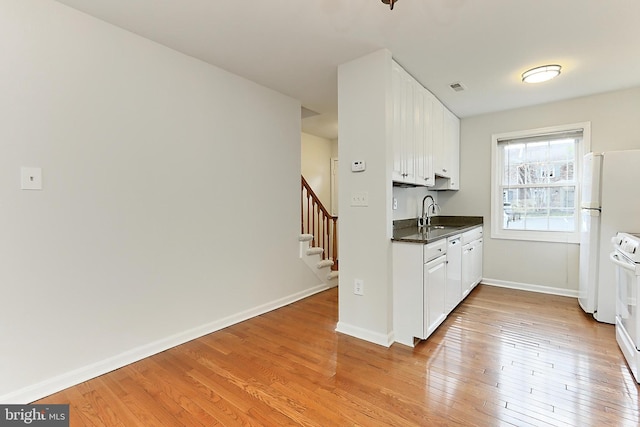 kitchen with white cabinets, dark countertops, visible vents, and light wood-style floors