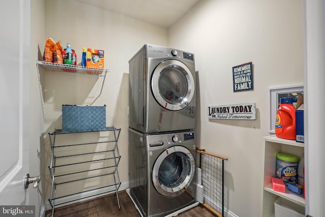 laundry area with baseboards, stacked washer / dryer, wood finished floors, and laundry area