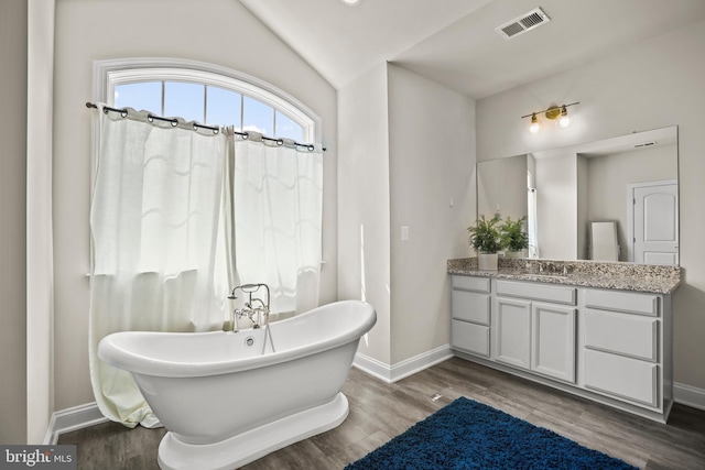 full bathroom with a freestanding tub, wood finished floors, visible vents, and baseboards