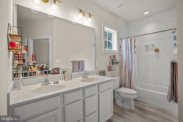 bathroom featuring visible vents, wood finished floors, a sink, and double vanity
