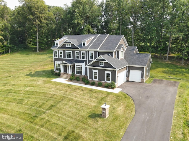 craftsman-style house featuring an attached garage, a porch, a front lawn, and aphalt driveway