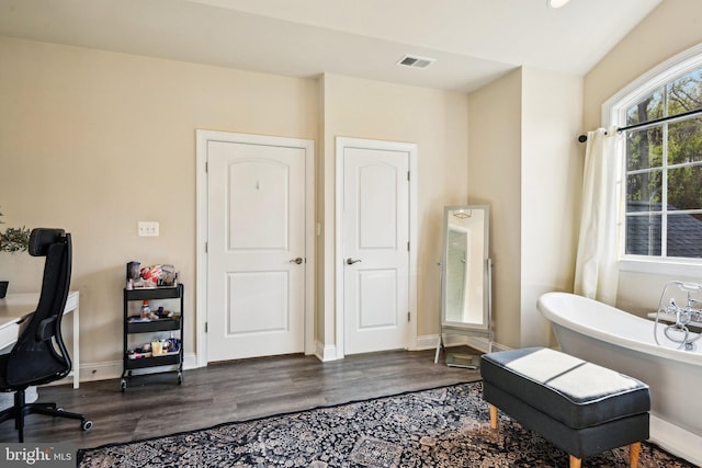 bathroom featuring a soaking tub, baseboards, wood finished floors, and visible vents