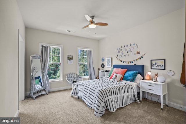 carpeted bedroom with visible vents, a ceiling fan, and baseboards