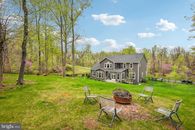 view of yard featuring fence, an outdoor fire pit, and a view of trees
