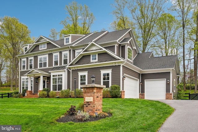 view of front facade with a shingled roof, driveway, a front yard, and a garage