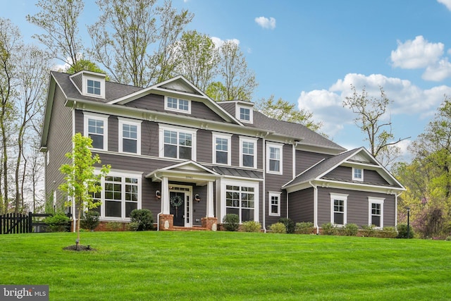 view of front facade with a front lawn, fence, and a shingled roof