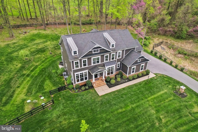 view of front of house featuring fence, roof with shingles, aphalt driveway, and a front yard