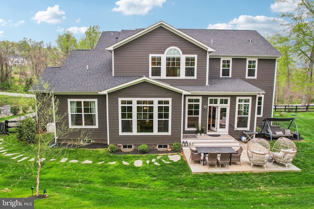 back of property featuring fence, a shingled roof, a yard, and a patio