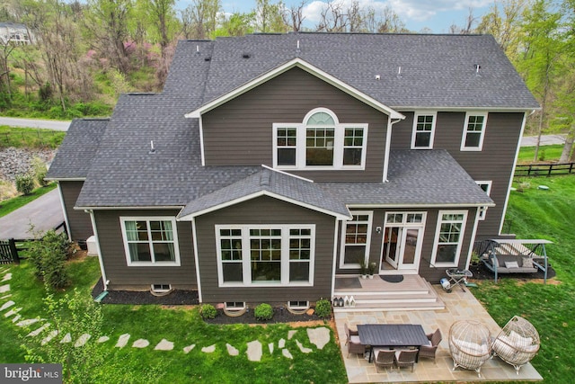 rear view of house featuring a shingled roof, an outdoor hangout area, a wooden deck, a patio, and a lawn