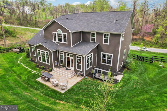 rear view of house featuring a yard, a shingled roof, a patio, and fence