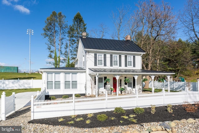 548 Uniontown Rd, Westminster, MD 21158 - back of house featuring a chimney, a fenced front yard, a standing seam roof, metal roof, and covered porch