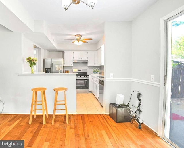 13059 Open Hearth Way, Germantown, MD 20874 - kitchen featuring a kitchen breakfast bar, appliances with stainless steel finishes, light wood-type flooring, a peninsula, and under cabinet range hood