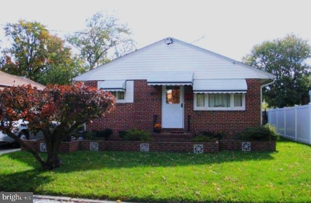 bungalow-style home with a front lawn, brick siding, and fence