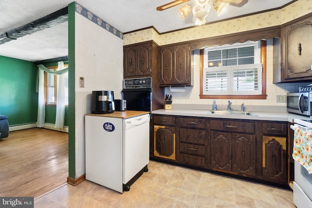 kitchen featuring oven, baseboards, a sink, and stainless steel microwave