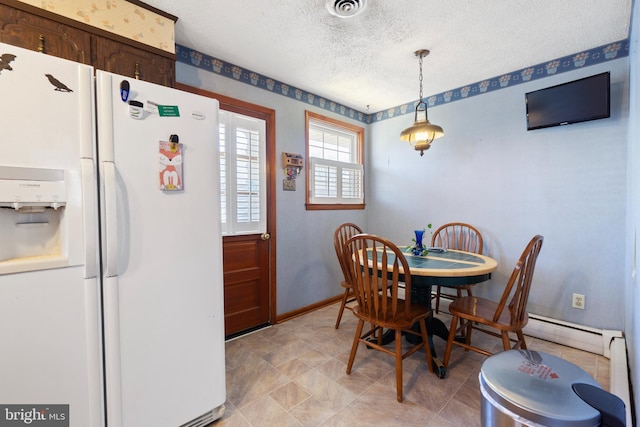 dining area with baseboard heating, a textured ceiling, baseboards, and visible vents