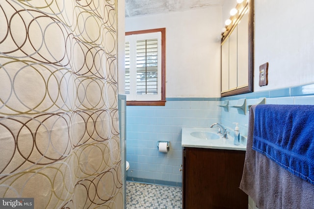 bathroom with tile walls, wainscoting, and vanity