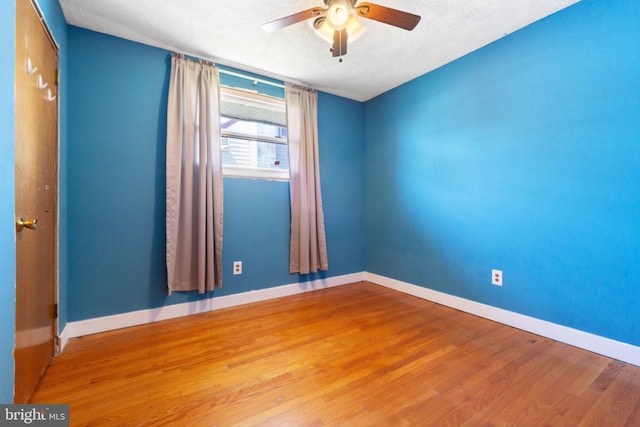 empty room featuring baseboards, a ceiling fan, wood finished floors, and a textured ceiling