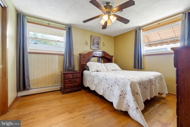bedroom with a baseboard heating unit, baseboards, a ceiling fan, and wood finished floors