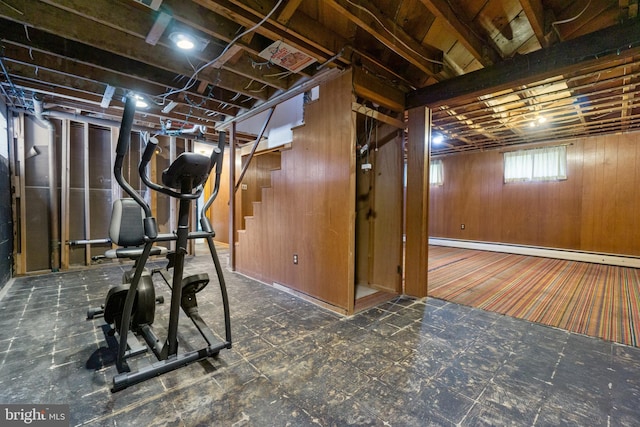 exercise room with tile patterned floors, baseboard heating, and wood walls