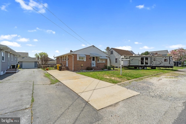 bungalow-style house featuring driveway, an outdoor structure, a front yard, brick siding, and a residential view