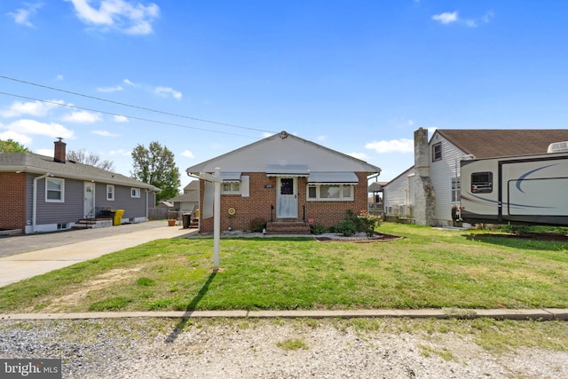 bungalow featuring brick siding, entry steps, and a front yard