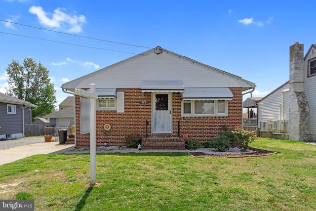 bungalow featuring fence, entry steps, a front yard, and brick siding