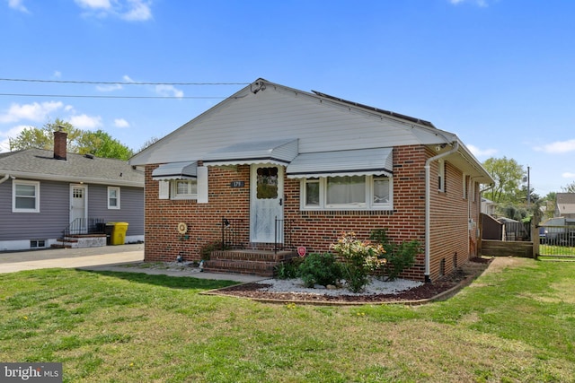 bungalow-style home featuring brick siding, entry steps, a front yard, and fence