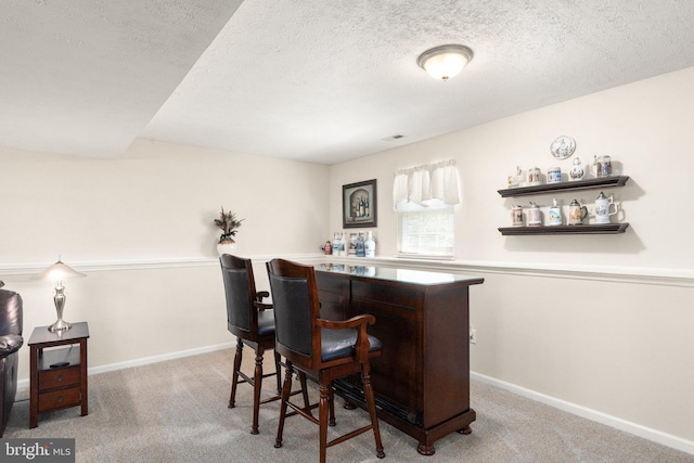 bar featuring baseboards, carpet flooring, and a textured ceiling