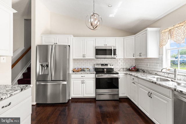 kitchen featuring a sink, appliances with stainless steel finishes, decorative backsplash, and lofted ceiling