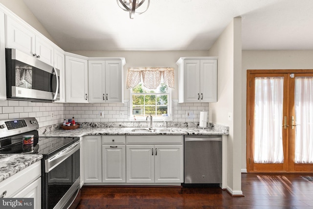 kitchen with dark wood-style flooring, a sink, stainless steel appliances, white cabinetry, and tasteful backsplash