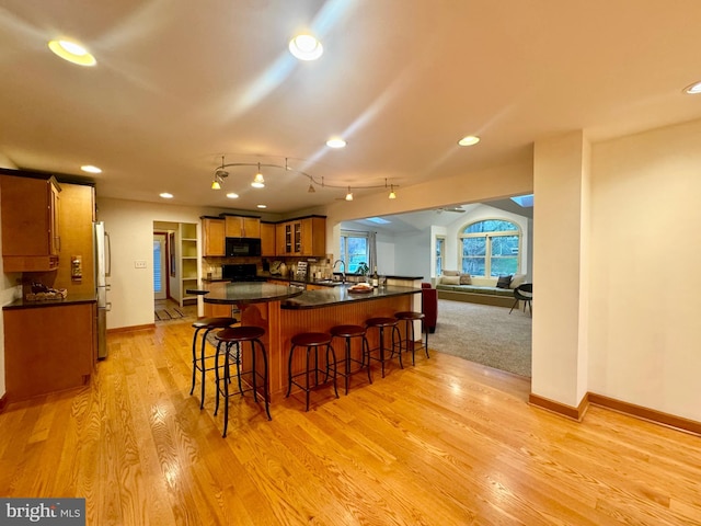 307 Homestead Rd, Hershey, PA 17033 - kitchen featuring dark countertops, a kitchen breakfast bar, a sink, black appliances, and baseboards