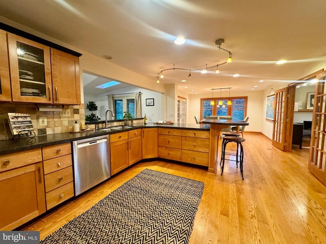 307 Homestead Rd, Hershey, PA 17033 - kitchen featuring a sink, glass insert cabinets, dishwasher, light wood-style flooring, and a kitchen bar