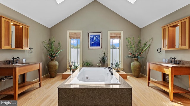 307 Homestead Rd, Hershey, PA 17033 - full bathroom featuring wood finished floors, a jetted tub, a sink, and vaulted ceiling with skylight