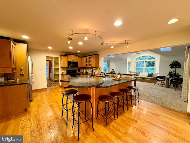 307 Homestead Rd, Hershey, PA 17033 - kitchen featuring a sink, glass insert cabinets, gas stove, black microwave, and a breakfast bar