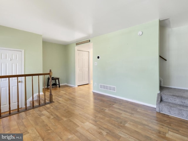 spare room featuring stairway, visible vents, baseboards, and light wood finished floors