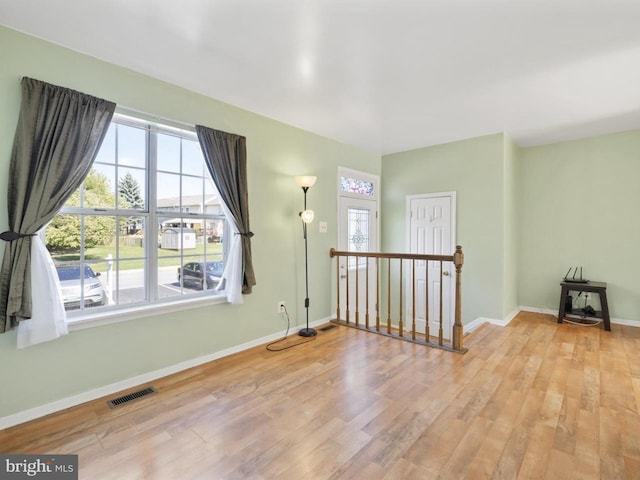 spare room featuring visible vents, baseboards, wood finished floors, and a wealth of natural light