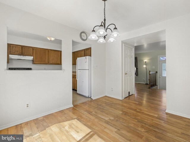unfurnished dining area featuring baseboards, light wood finished floors, and a notable chandelier