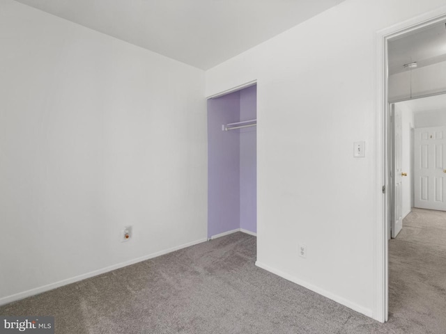 unfurnished bedroom with baseboards, carpet flooring, and a closet