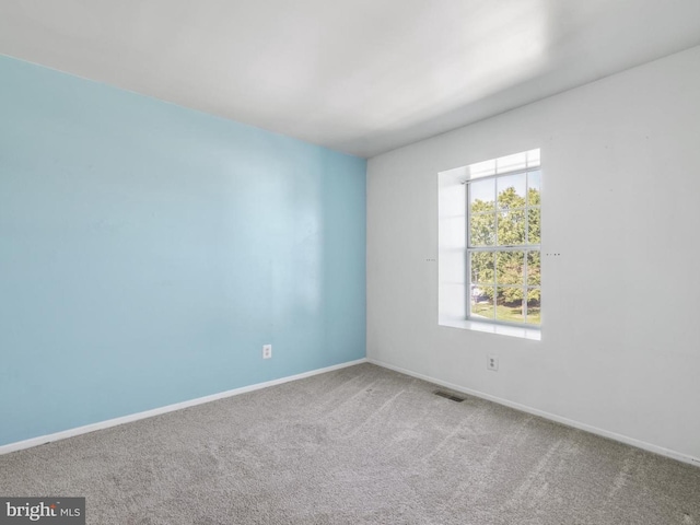 carpeted empty room featuring baseboards and visible vents