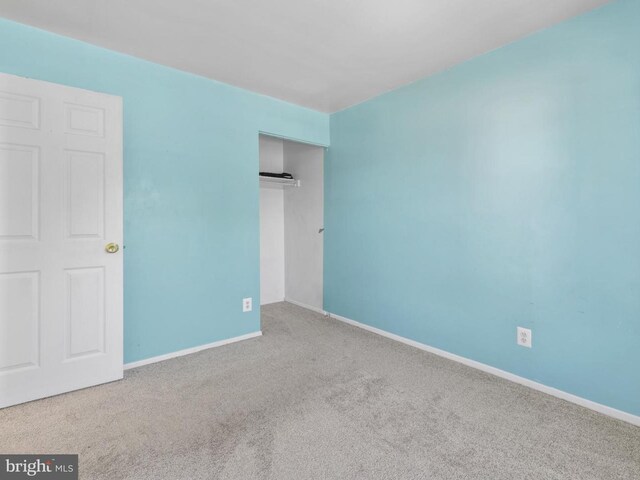unfurnished bedroom featuring baseboards, carpet, and a closet