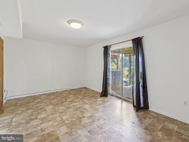 spare room with baseboards and stone finish floor