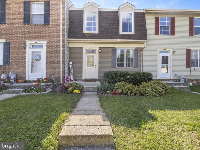multi unit property featuring mansard roof, a shingled roof, and a front yard