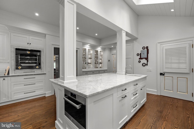 6068 Stoney Hill Rd, New Hope, PA 18938 - kitchen with wall oven, a sink, dark wood finished floors, ornate columns, and light stone countertops