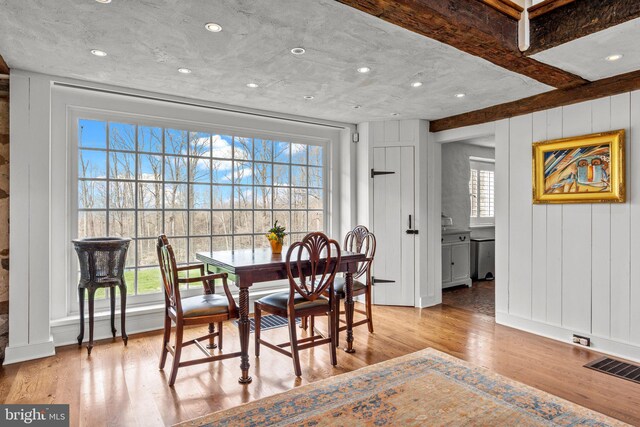 6068 Stoney Hill Rd, New Hope, PA 18938 - dining space featuring beamed ceiling, a decorative wall, wood finished floors, and visible vents