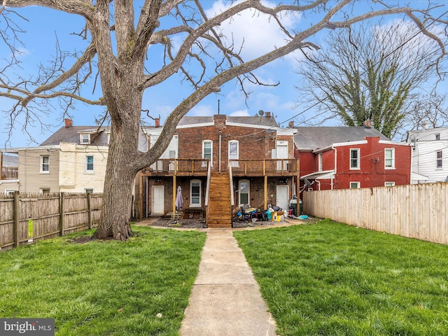 rear view of property featuring a fenced backyard, a wooden deck, a yard, and brick siding