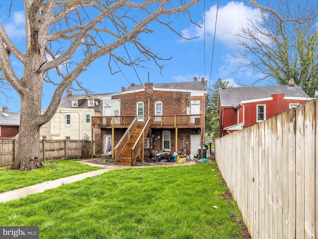 back of house with stairs, brick siding, a deck, a fenced backyard, and a lawn