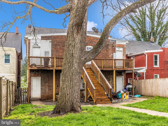 rear view of property with a fenced backyard, a wooden deck, stairway, and brick siding