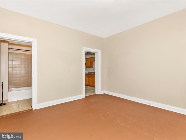 unfurnished bedroom featuring baseboards and ensuite bathroom